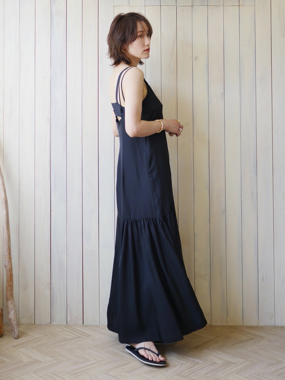 ブラック系のワンピース、ブラック系のサンダル、ゴールド系のピアス（両耳用）を着用したレディースの夏コーディネートの2枚目の写真