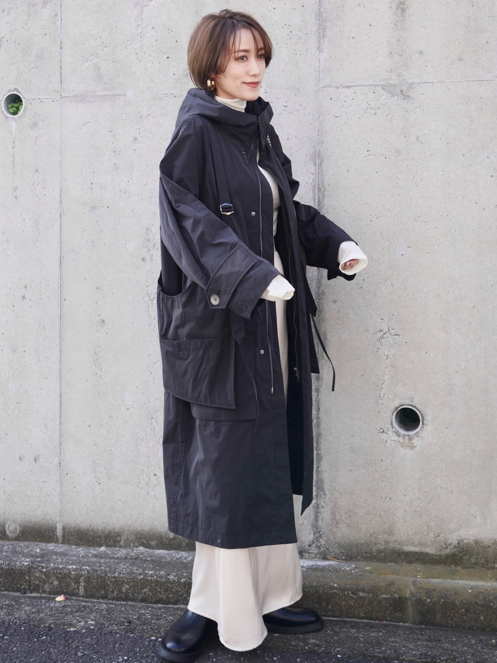 ブラック系のその他アウター、ホワイト系のスカート、ブラック系のブーツを着用したレディースの秋コーディネートの2枚目の写真