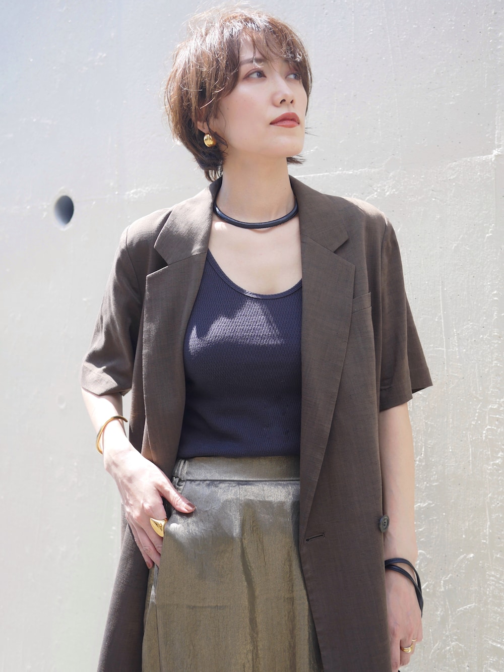 ゴールド系のスカート、ブラウン系のテーラードジャケット、ブラック系のタンクトップを着用したレディースの秋コーディネートの3枚目の写真