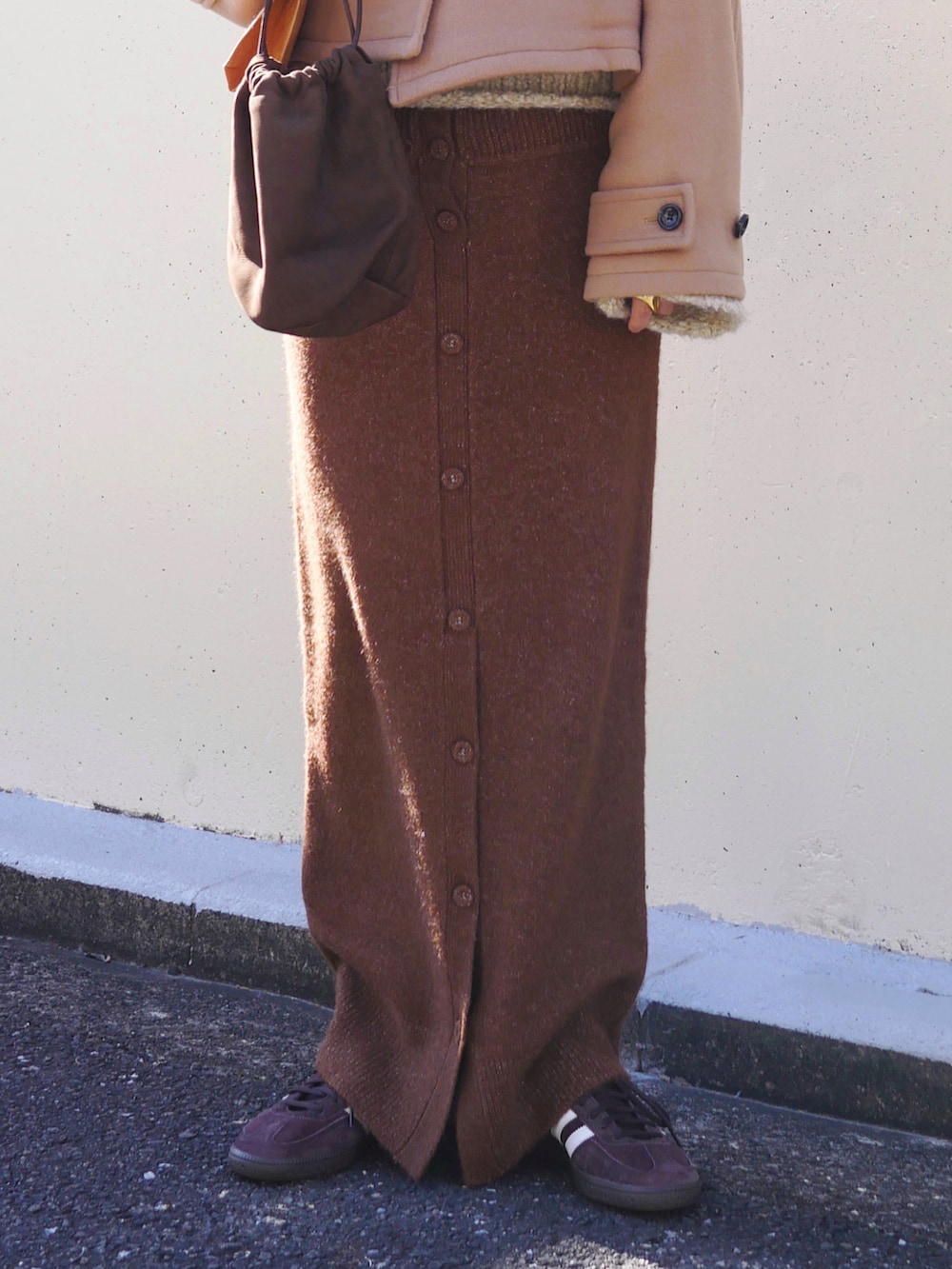 ベージュ系のピーコート、ブラウン系のスカート、ブラウン系のトートバッグを着用したレディースの冬コーディネートの2枚目の写真