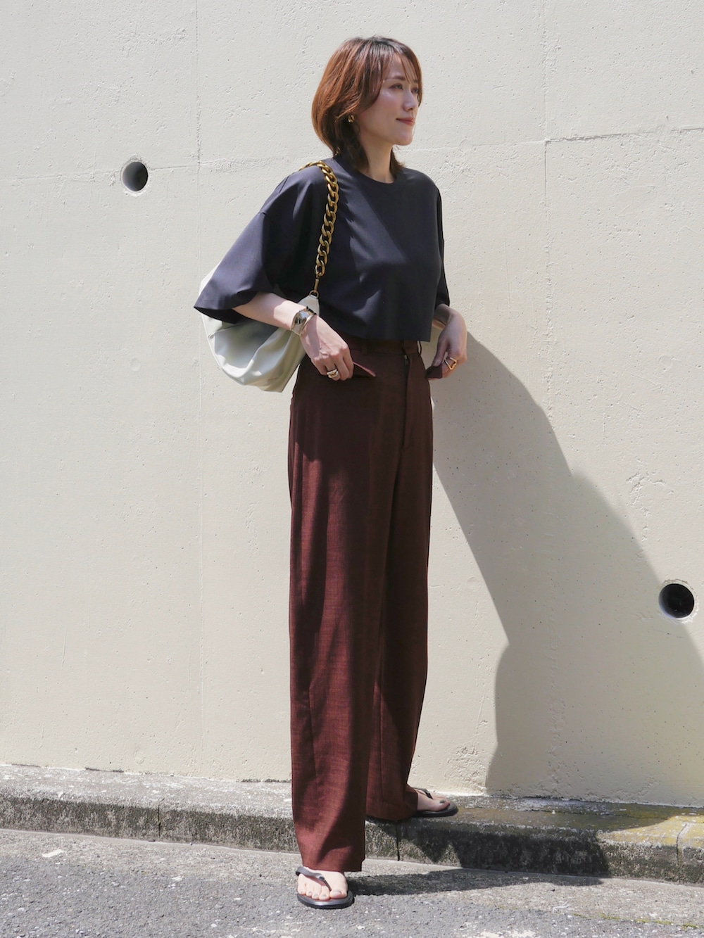 レッド系のスラックス、ホワイト系のショルダーバッグ、ブラック系のTシャツ/カットソーを着用したレディースの春コーディネートの3枚目の写真