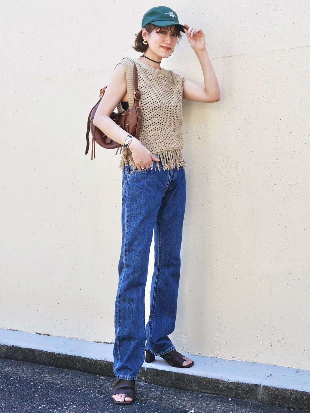 ベージュ系のニット/セーター、ブルー系のデニムパンツ、ブラウン系のバッグを着用したレディースの夏コーディネートの2枚目の写真