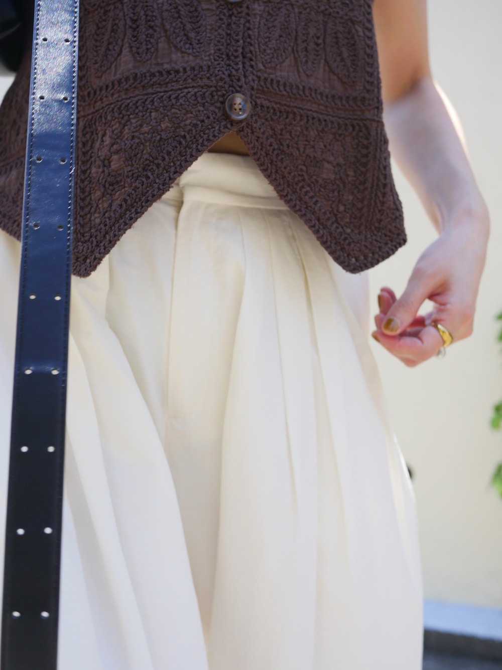 ブラウン系のベスト、ホワイト系のその他パンツ、ブラック系のサンダルを着用したレディースの夏コーディネートの3枚目の写真