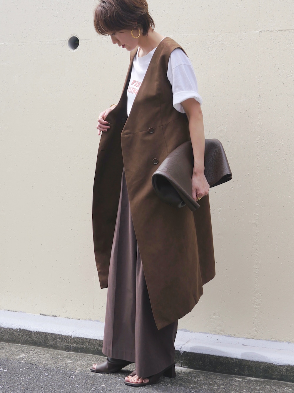 ブラウン系のハンドバッグ、イエロー系のワンピース/ドレス、ブラウン系のサンダルを着用したレディースの秋コーディネートの3枚目の写真