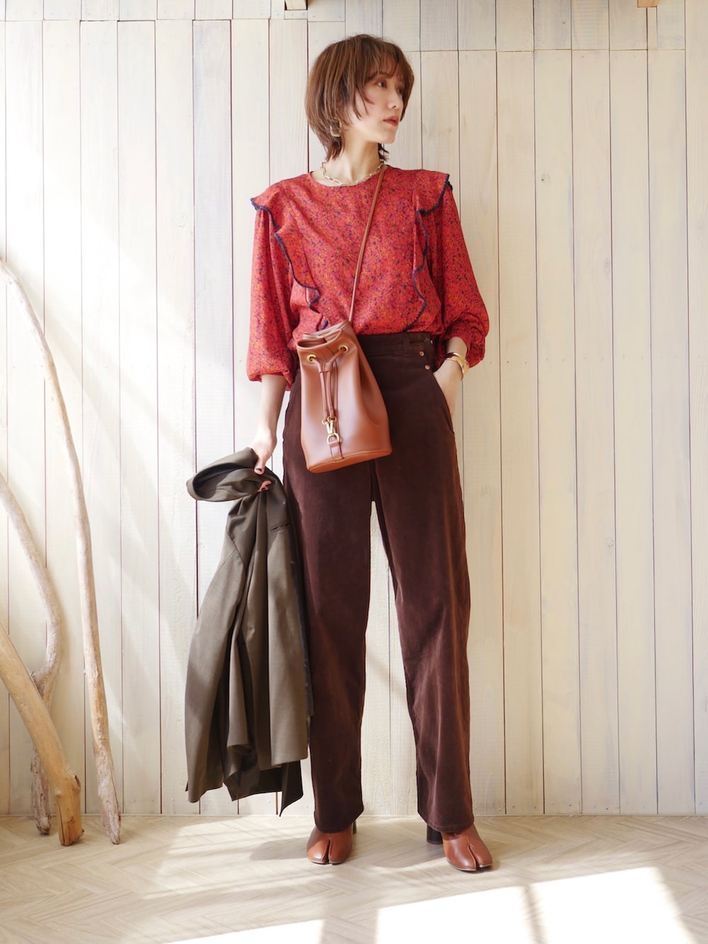 レッド系のシャツ/ブラウス、グリーン系のテーラードジャケット、ブラウン系のブーツを着用したレディースの春コーディネートの2枚目の写真