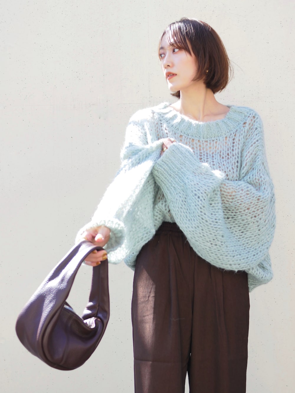 グリーン系のニット/セーター、ブラウン系のスラックス、レッド系のハンドバッグを着用したレディースの秋コーディネートの3枚目の写真