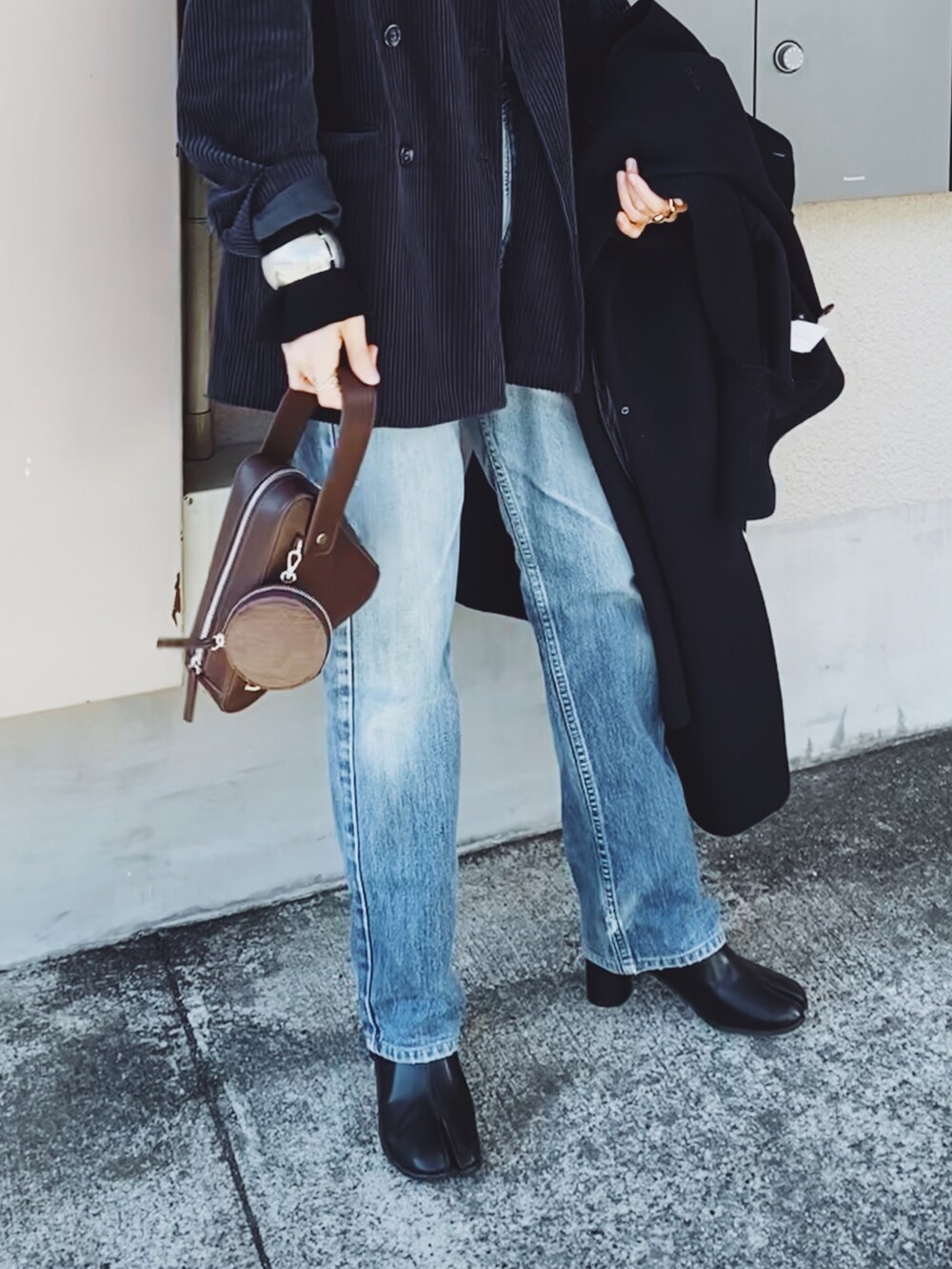 ブルー系のテーラードジャケット、ブラウン系のショルダーバッグ、ブラック系のニット/セーターを着用したレディースの冬コーディネートの2枚目の写真