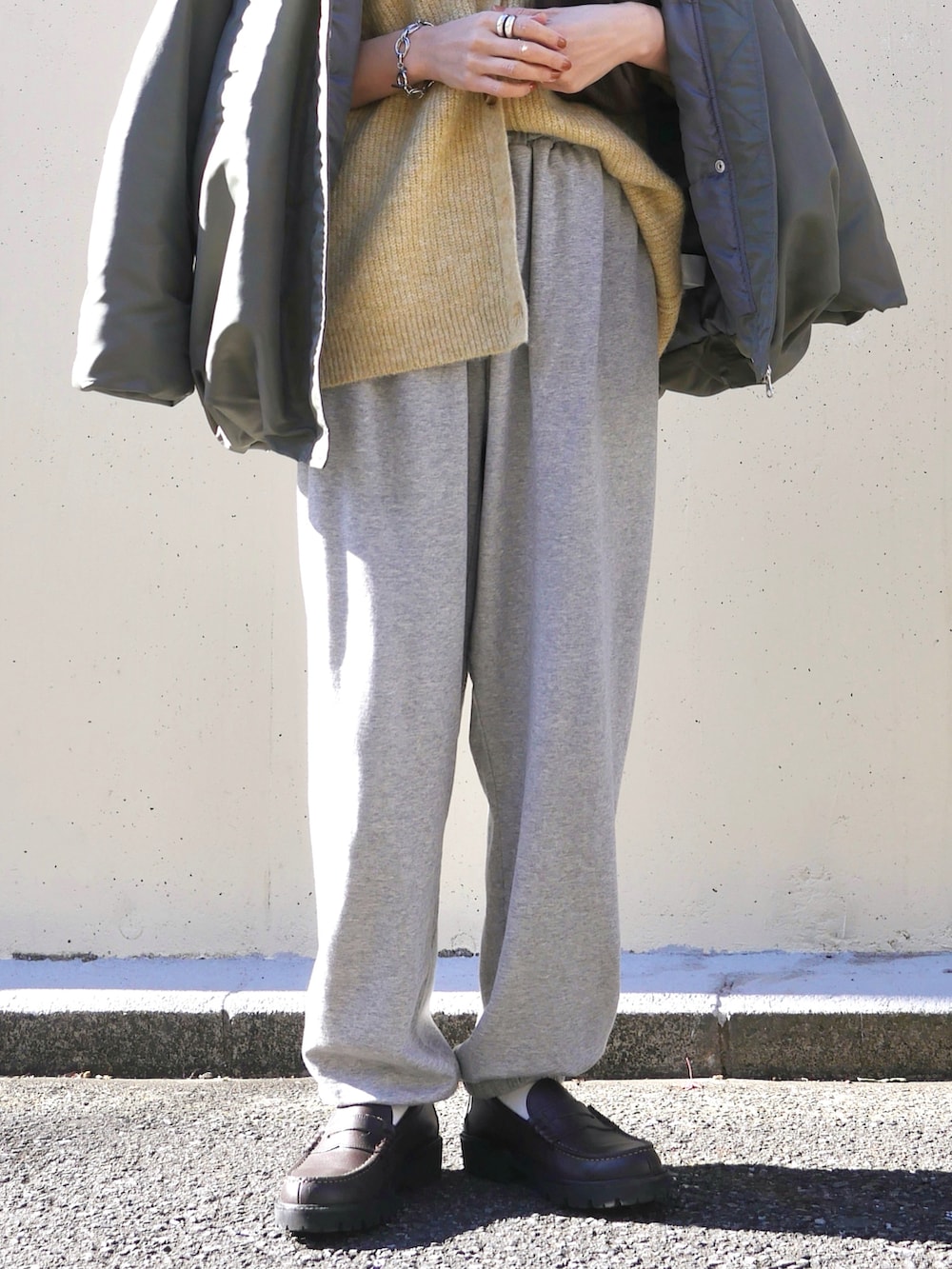 イエロー系のカーディガン/ボレロ、グリーン系のブルゾン、グレー系のスウェットパンツを着用したレディースの冬コーディネートの3枚目の写真