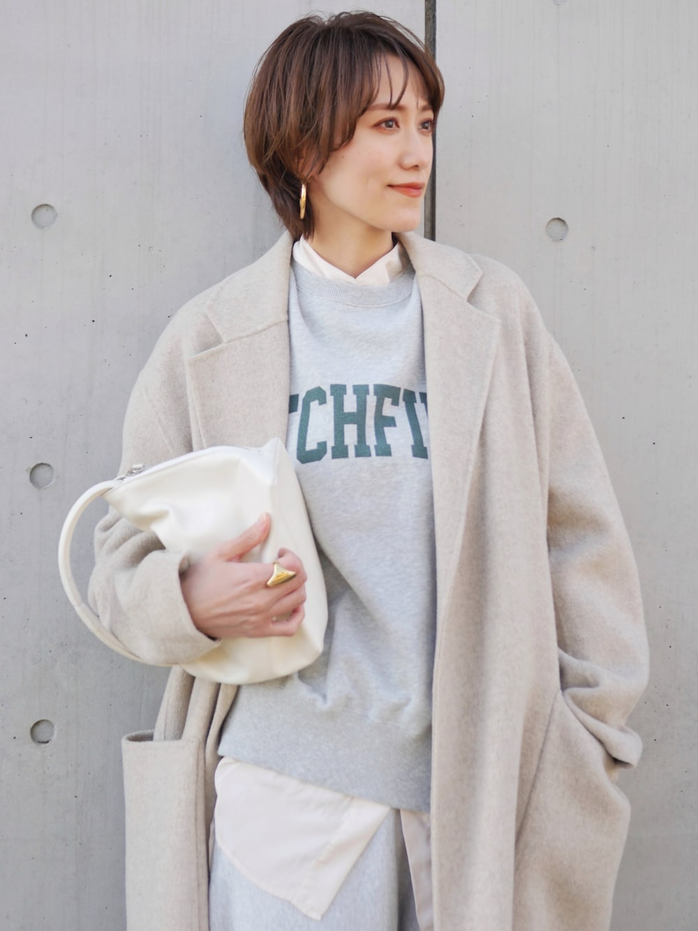 グレー系のスウェットパンツ、ホワイト系のスニーカー、ホワイト系のハンドバッグを着用したレディースの冬コーディネートの2枚目の写真