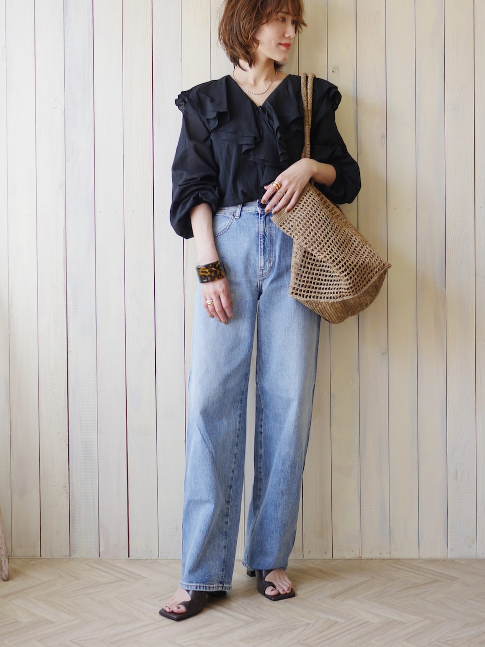 ブラック系のシャツ/ブラウス、ブラウン系のかごバッグ、ブルー系のデニムパンツを着用したレディースの夏コーディネートの2枚目の写真