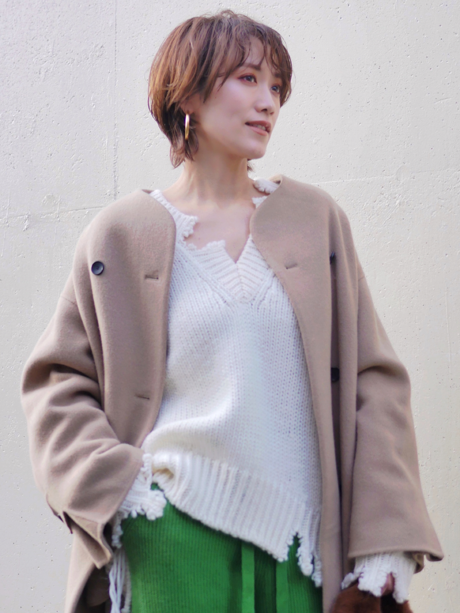 ホワイト系のニット/セーター、グリーン系のスラックス、ベージュ系のその他アウターを着用したレディースの冬コーディネートの2枚目の写真