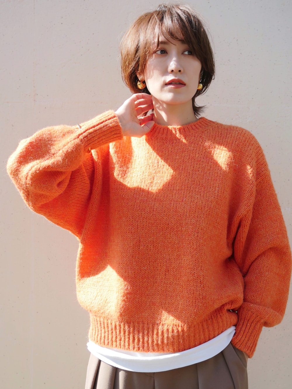 オレンジ系のニット/セーター、ベージュ系のその他パンツ、イエロー系のショルダーバッグを着用したレディースの秋コーディネートの2枚目の写真