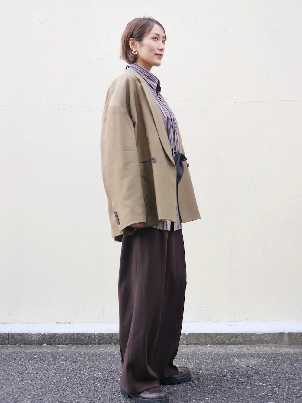 グリーン系のテーラードジャケット、ブラウン系のスラックス、ブラウン系のローファーを着用したレディースの秋コーディネートの3枚目の写真