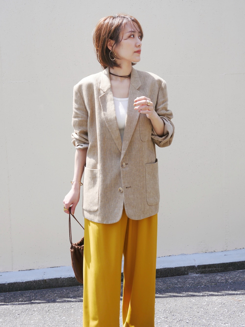 ベージュ系のテーラードジャケット、イエロー系のその他パンツ、ブラウン系のスニーカーを着用したレディースの春コーディネートの2枚目の写真