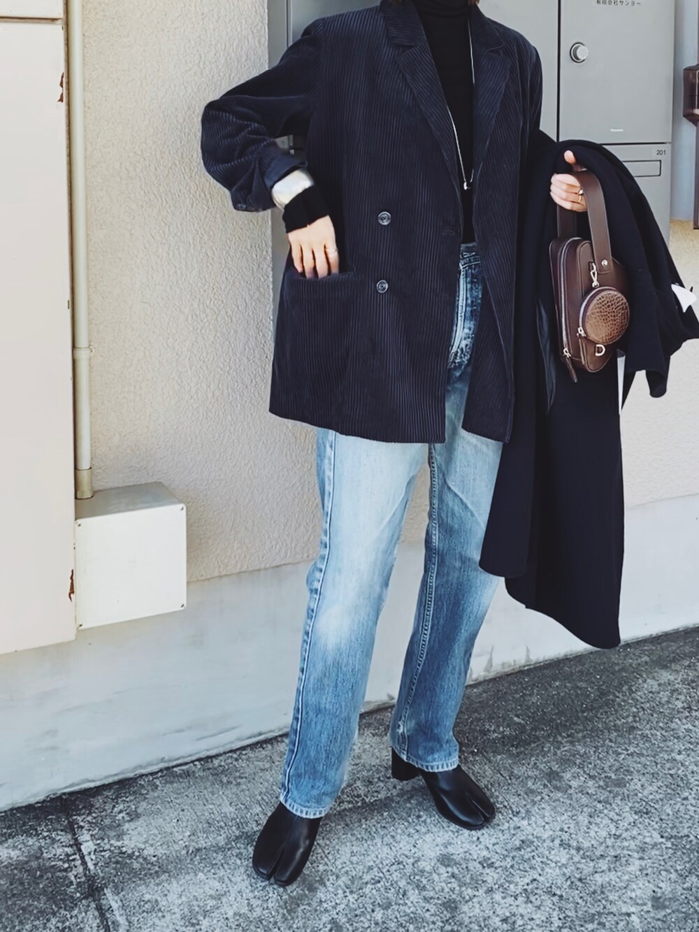 ブルー系のテーラードジャケット、ブラウン系のショルダーバッグ、ブラック系のニット/セーターを着用したレディースの冬コーディネートの3枚目の写真