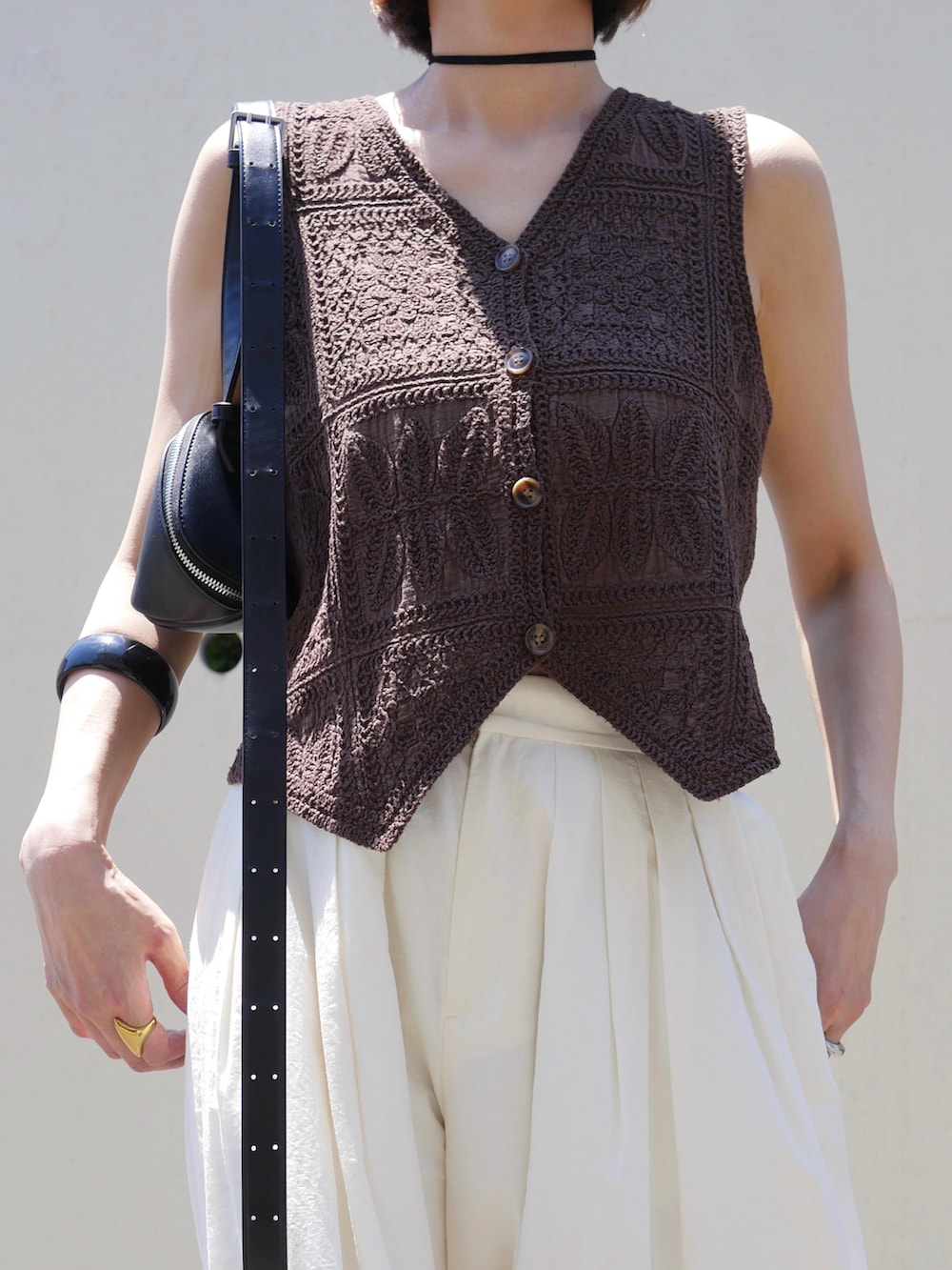 ブラウン系のベスト、ホワイト系のその他パンツ、ブラック系のサンダルを着用したレディースの夏コーディネートの2枚目の写真