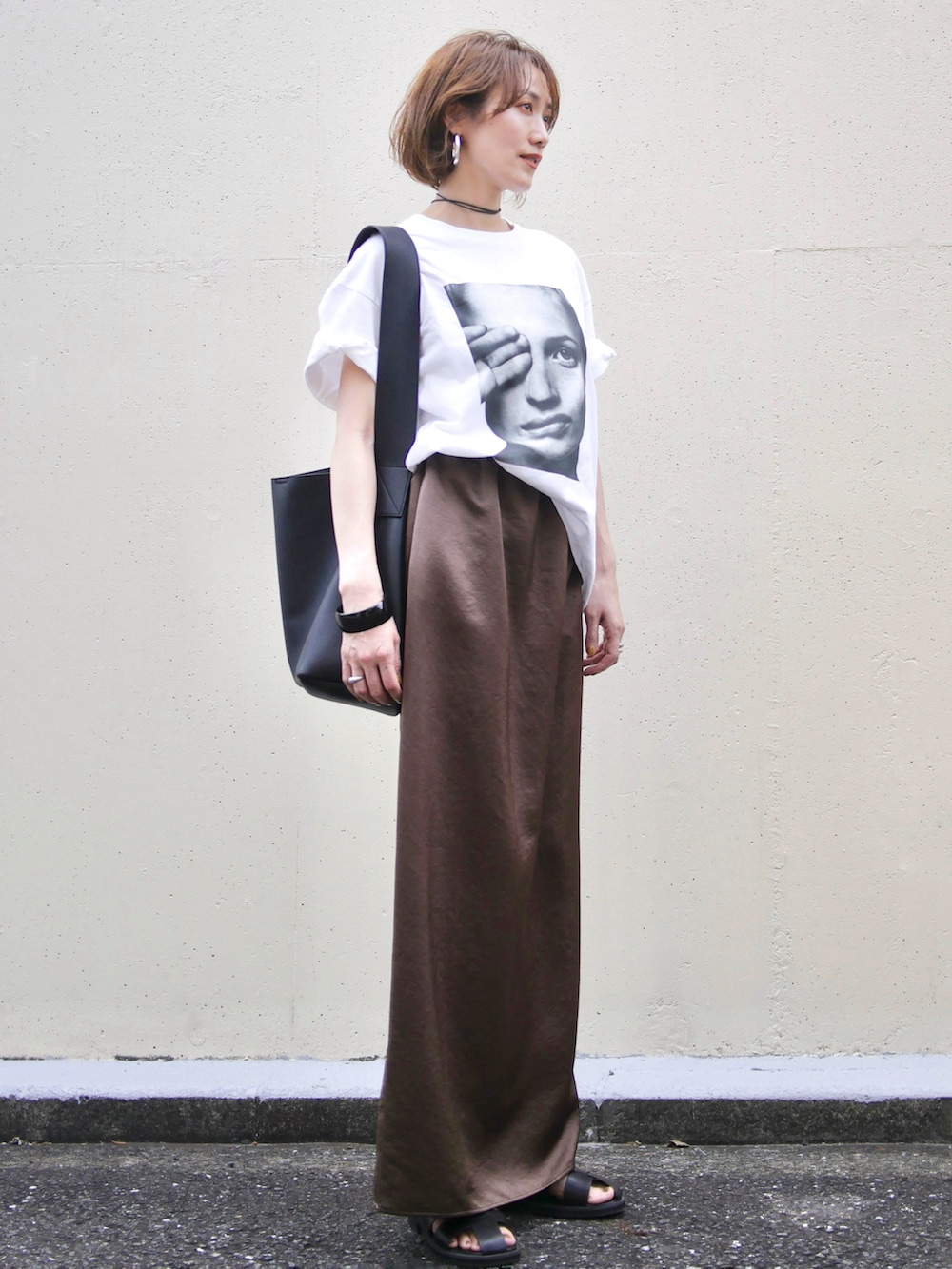 ブラウン系のスカート、ブラック系のサンダル、ブラック系のショルダーバッグを着用したレディースの夏コーディネートの2枚目の写真