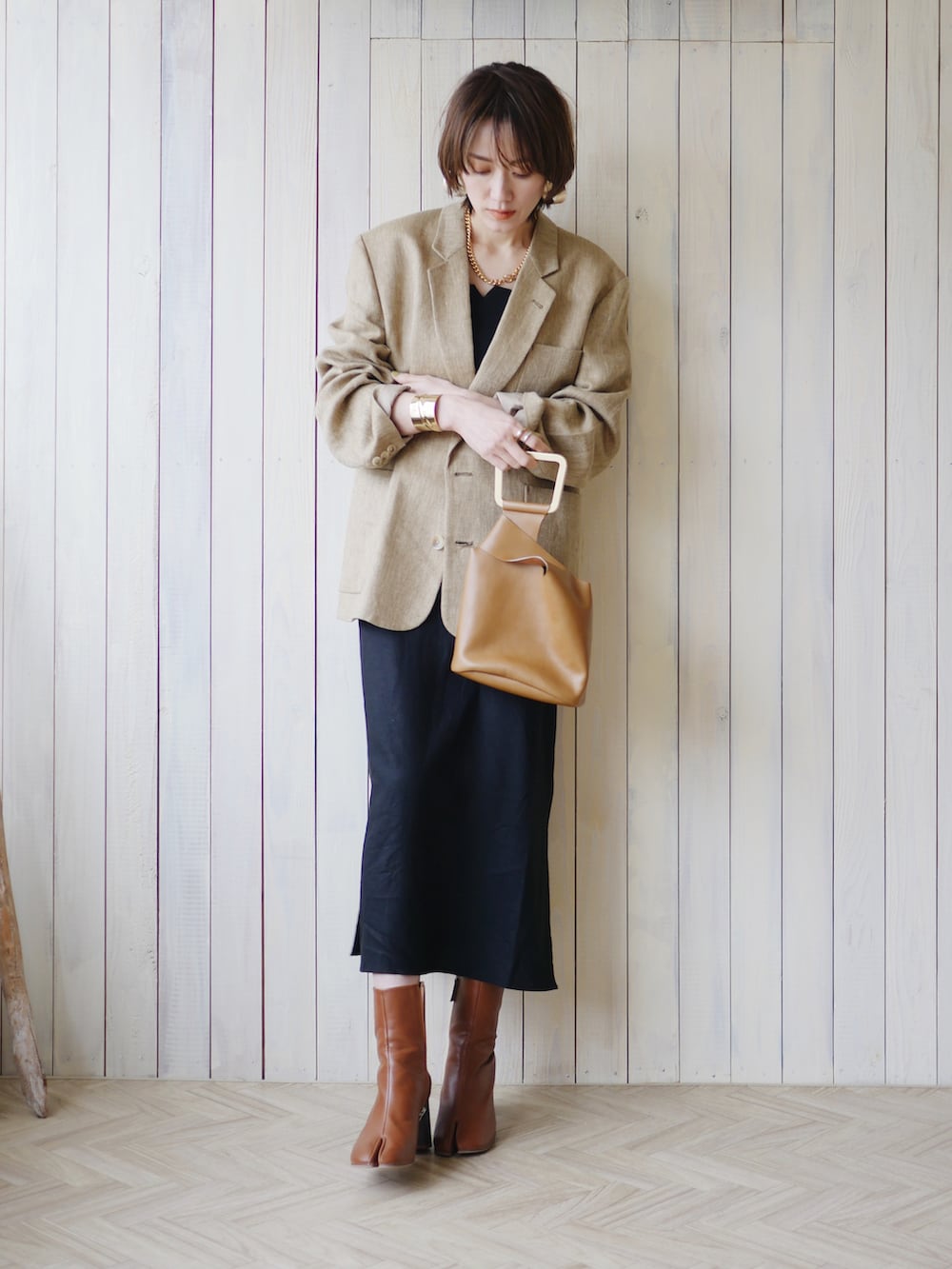 ベージュ系のテーラードジャケット、ブラック系のワンピース、ブラウン系のブーツを着用したレディースの春コーディネートの2枚目の写真