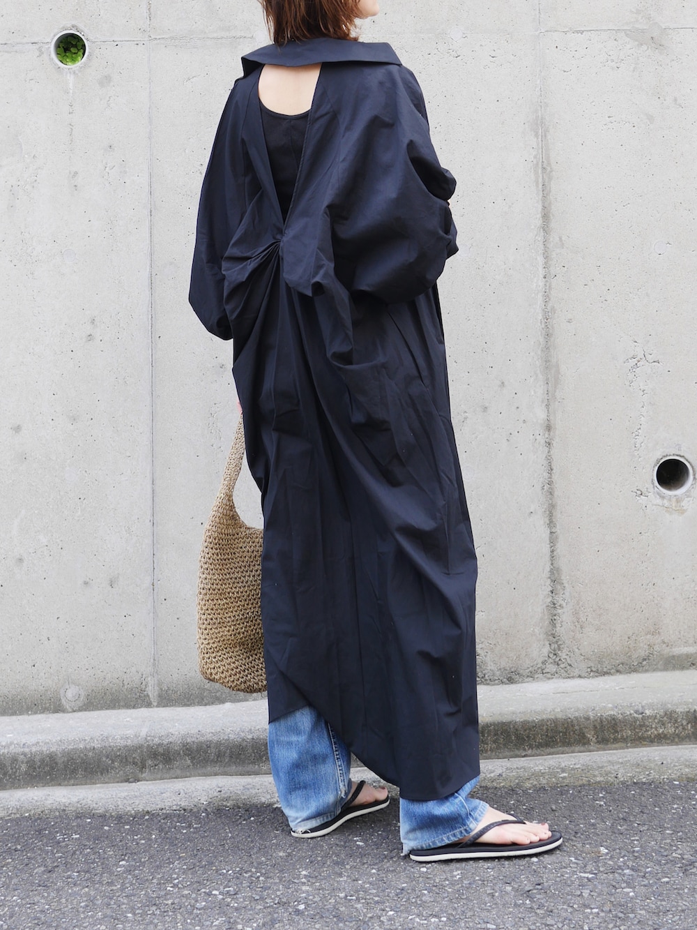 ブラック系のワンピース、ブラック系のサンダル、ベージュ系のトートバッグを着用したレディースの夏コーディネートの3枚目の写真