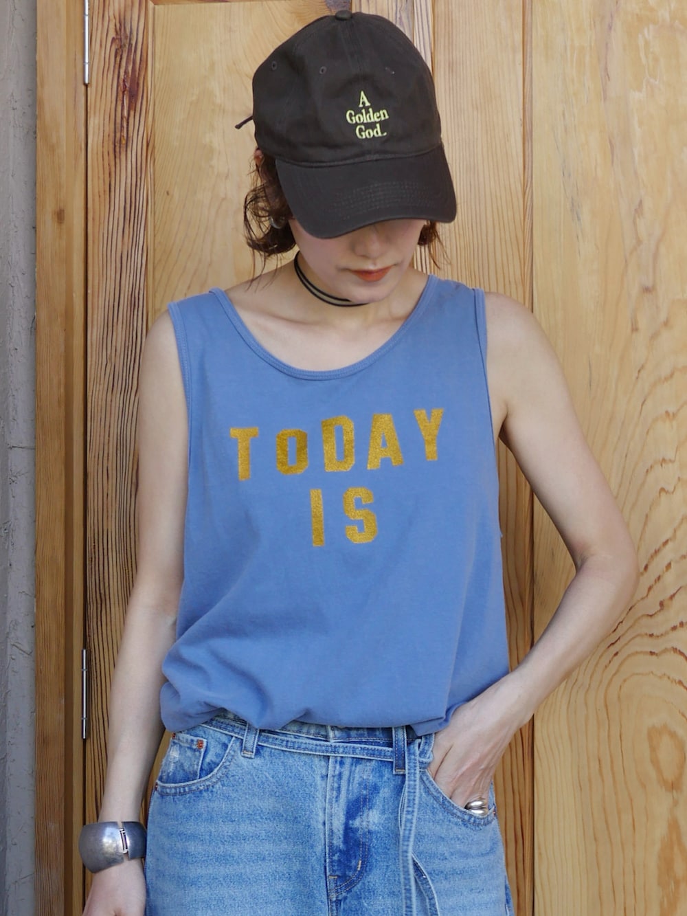 ブルー系のタンクトップ、ブルー系のデニムパンツ、ブラウン系のかごバッグを着用したレディースの夏コーディネートの3枚目の写真