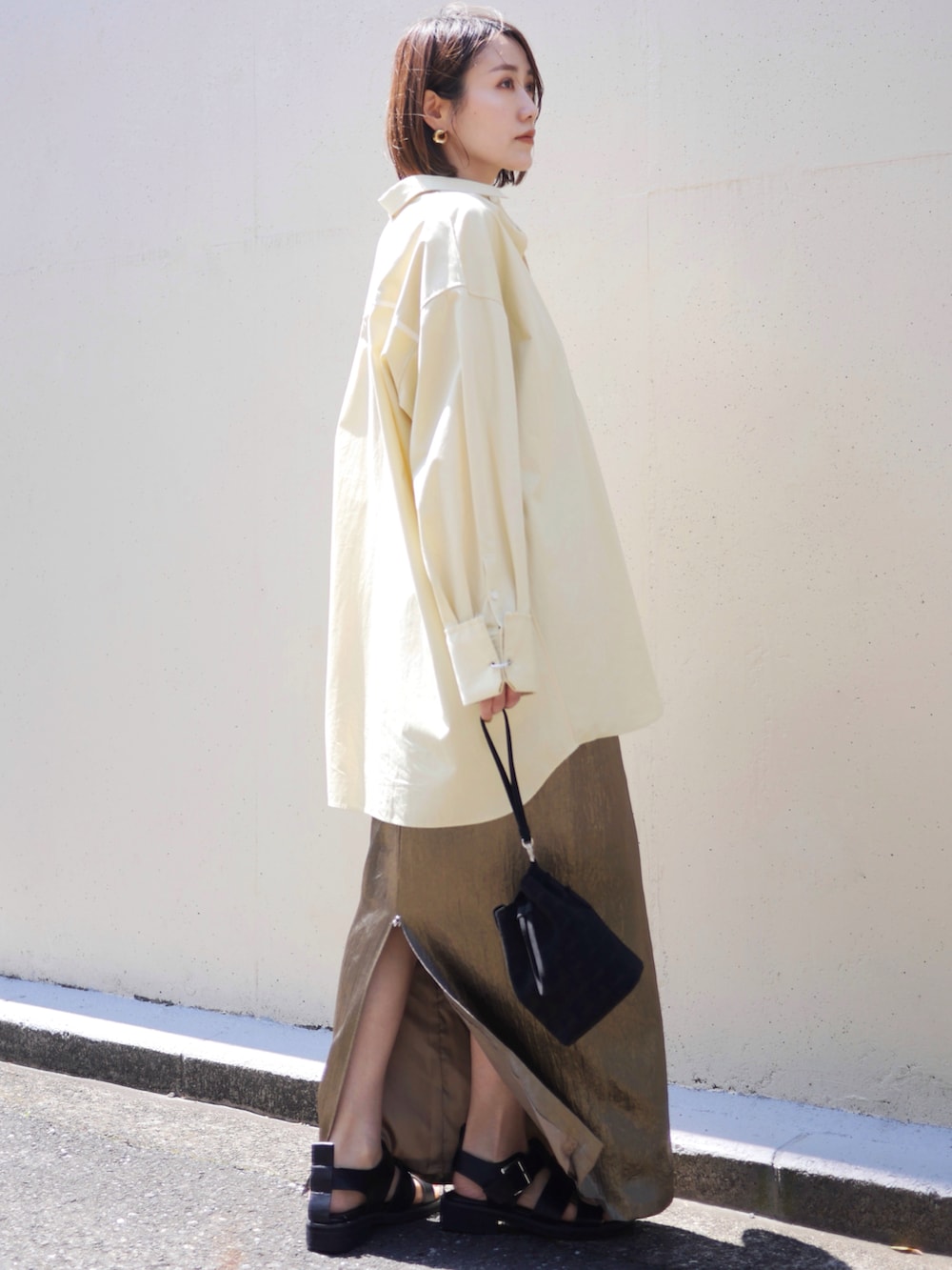 イエロー系のシャツ/ブラウス、ゴールド系のスカート、ブラック系のサンダルを着用したレディースの春コーディネートの3枚目の写真