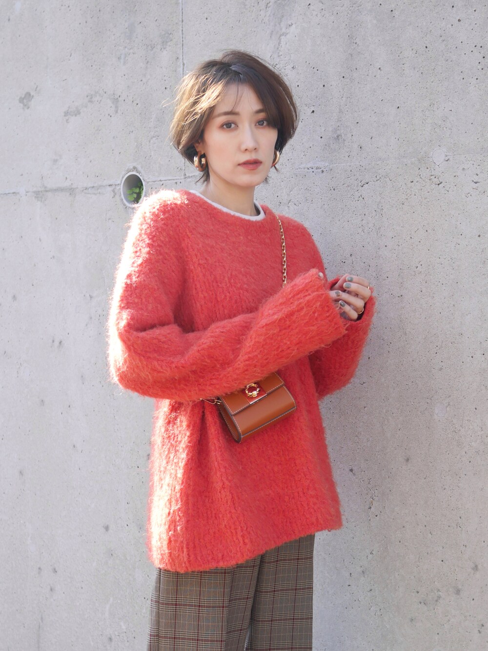 ブラウン系のパンツ、オレンジ系のニット/セーター、イエロー系のショルダーバッグを着用したレディースの秋コーディネートの3枚目の写真