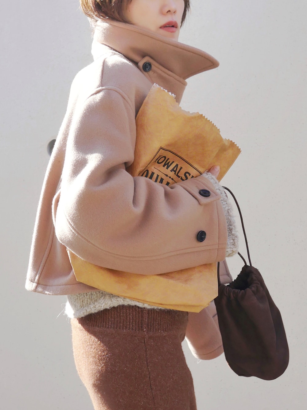 ベージュ系のピーコート、ブラウン系のスカート、ブラウン系のトートバッグを着用したレディースの冬コーディネートの4枚目の写真