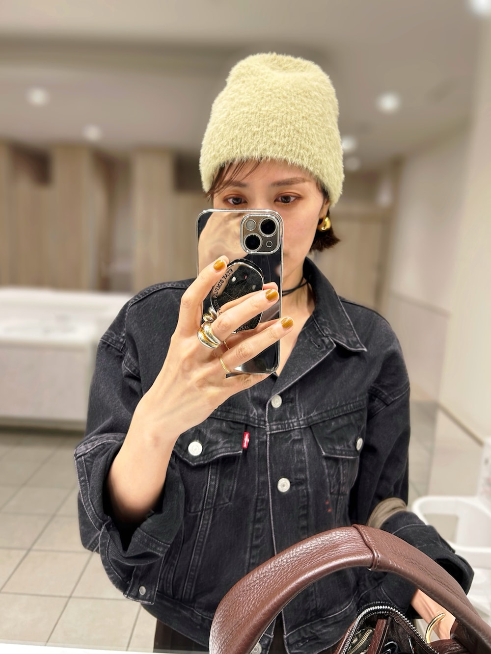 ブラック系のデニムジャケット、レッド系のハンドバッグ、ブラウン系のスラックスを着用したレディースの秋コーディネートの2枚目の写真