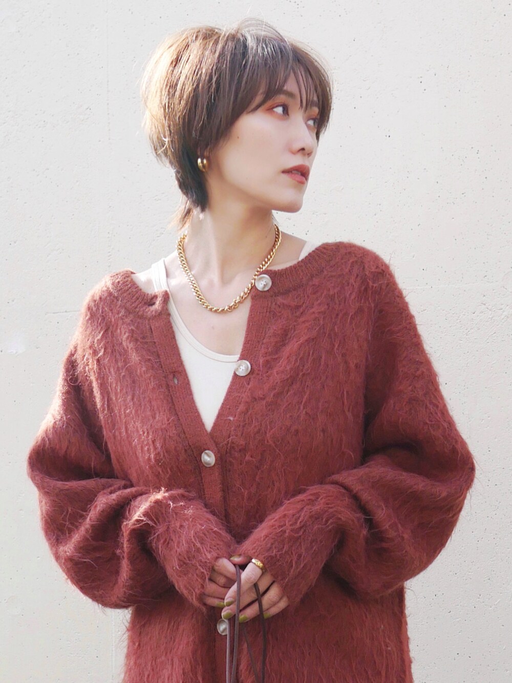 オレンジ系のカーディガン/ボレロ、ブラウン系のスカート、ブラウン系のトートバッグを着用したレディースの冬コーディネートの2枚目の写真