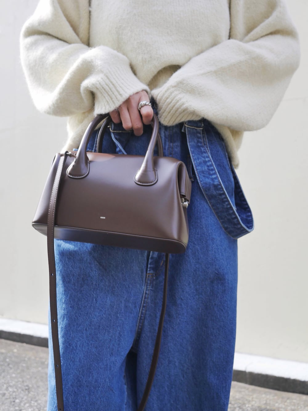 ホワイト系のニット/セーター、ブルー系のサロペット/オーバーオール、ブラウン系のショルダーバッグを着用したレディースの冬コーディネートの2枚目の写真