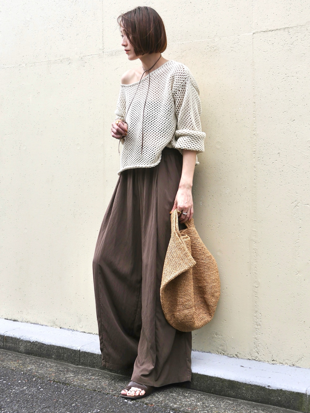 ホワイト系のニット/セーター、ブラウン系のその他パンツ、ブラウン系のかごバッグを着用したレディースの夏コーディネートの2枚目の写真