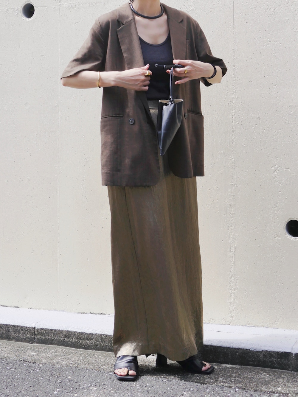 ゴールド系のスカート、ブラウン系のテーラードジャケット、ブラック系のタンクトップを着用したレディースの秋コーディネートの4枚目の写真