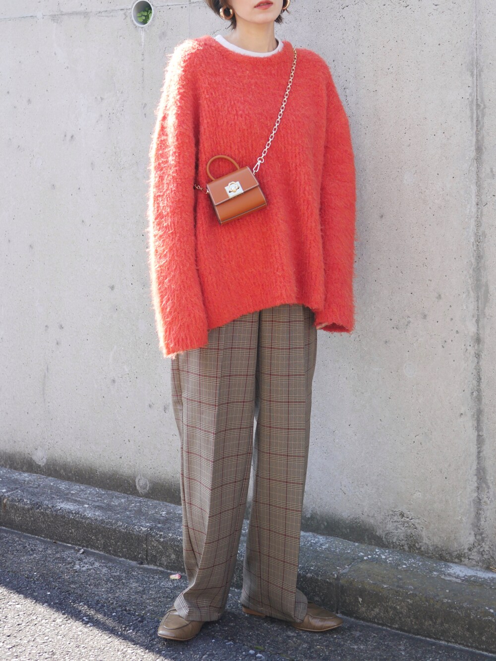 ブラウン系のパンツ、オレンジ系のニット/セーター、イエロー系のショルダーバッグを着用したレディースの秋コーディネートの2枚目の写真
