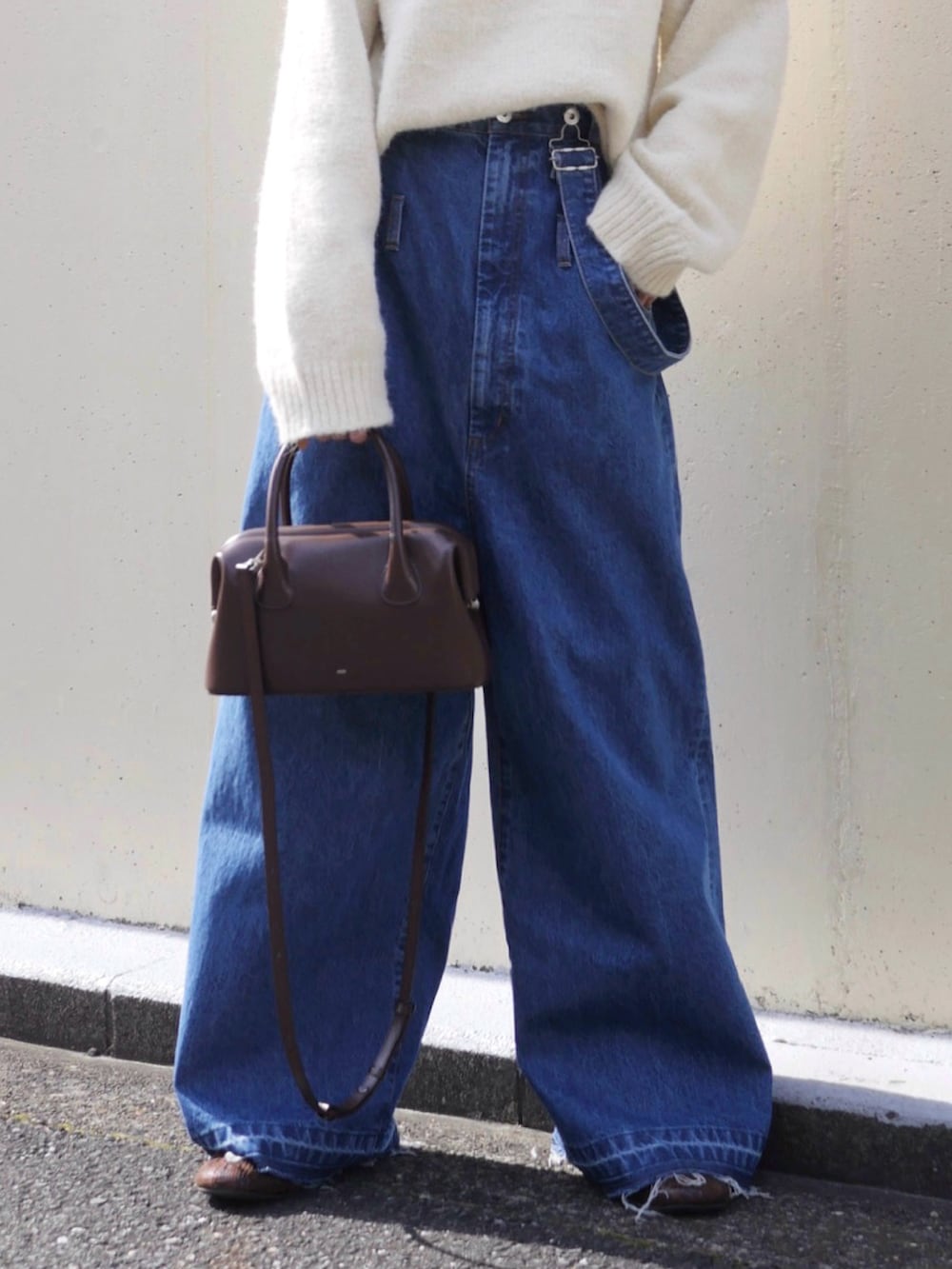 ホワイト系のニット/セーター、ブルー系のサロペット/オーバーオール、ブラウン系のショルダーバッグを着用したレディースの冬コーディネートの4枚目の写真