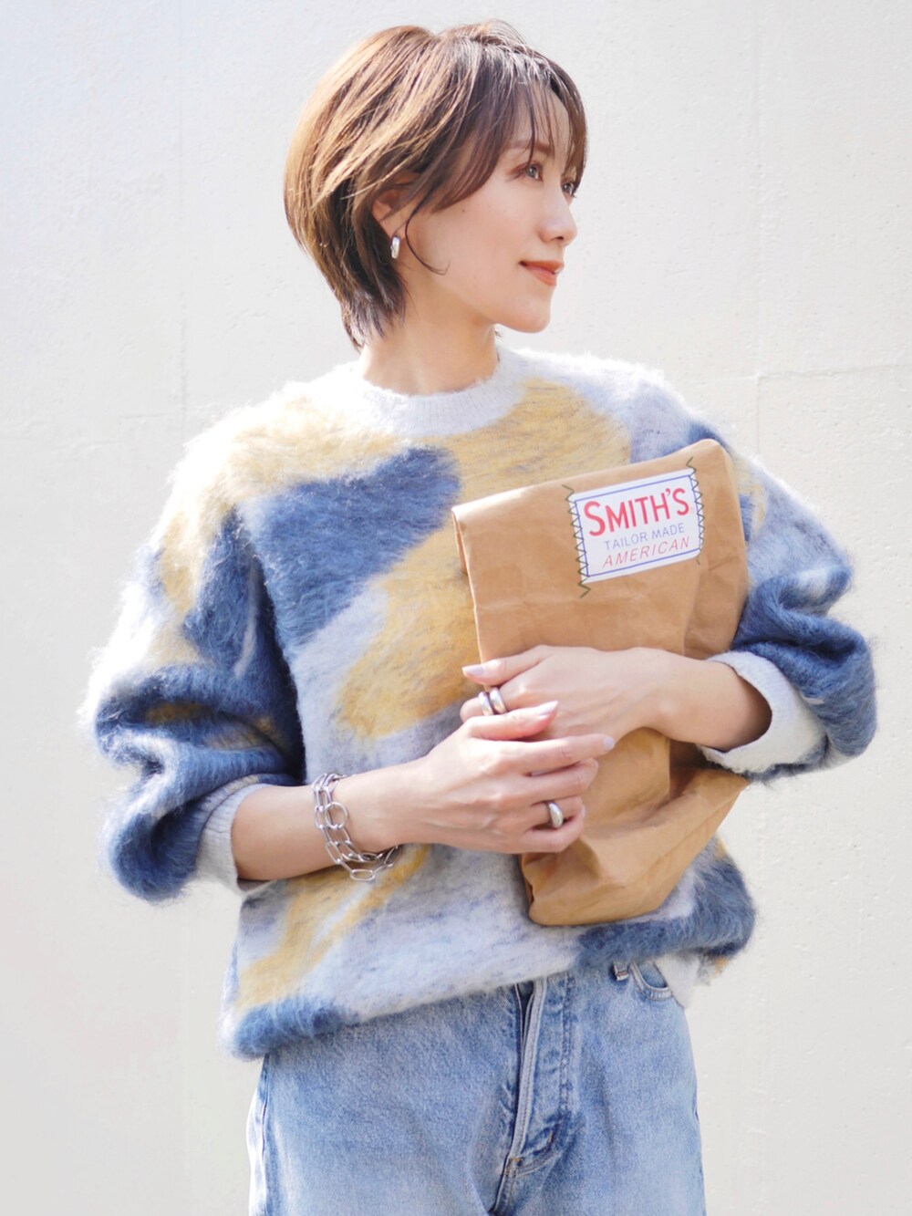 ブルー系のニット/セーター、ベージュ系のトートバッグ、シルバー系のピアス（両耳用）を着用したレディースの秋コーディネートの2枚目の写真