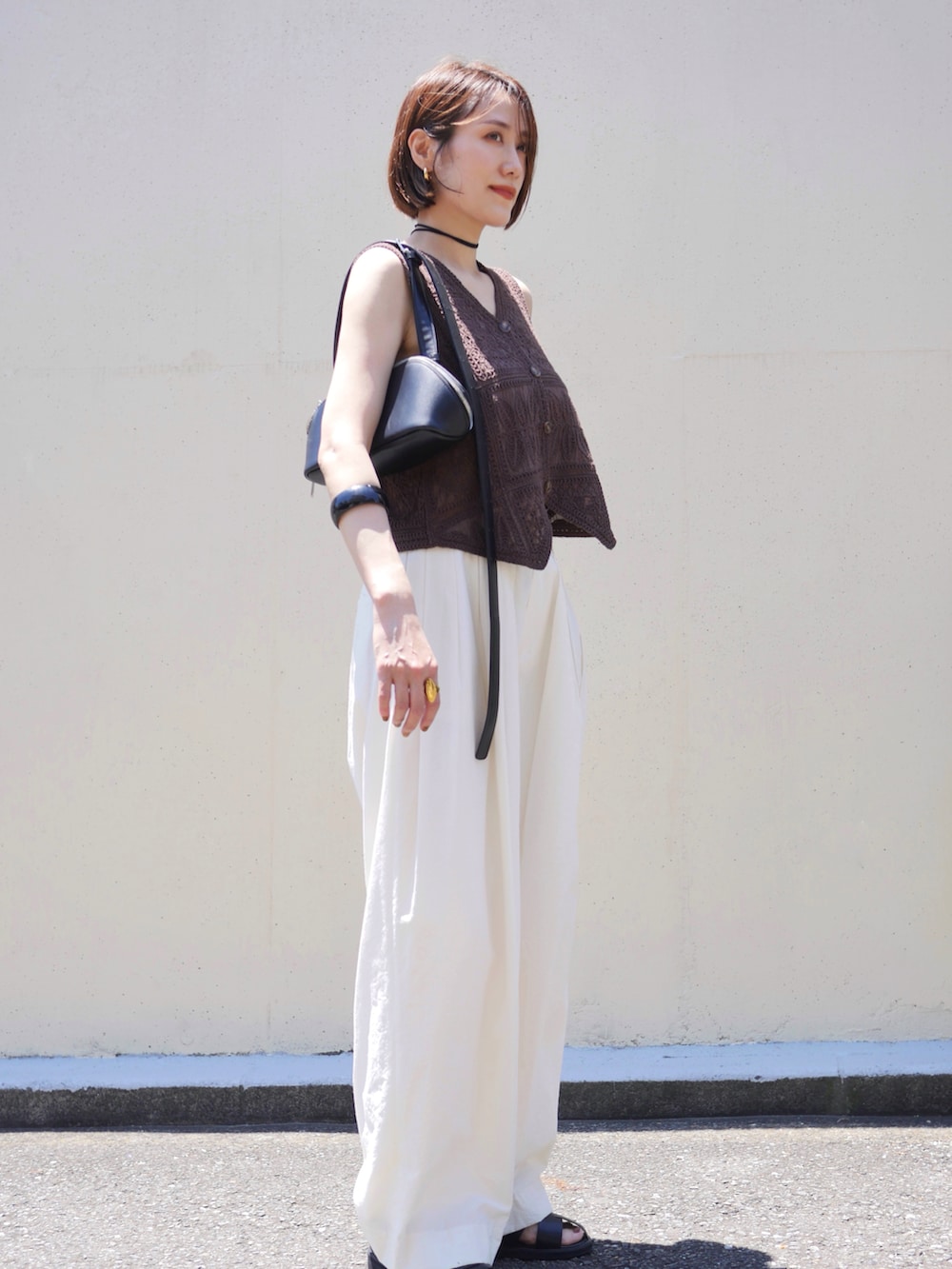 ブラウン系のベスト、ホワイト系のその他パンツ、ブラック系のサンダルを着用したレディースの夏コーディネートの4枚目の写真