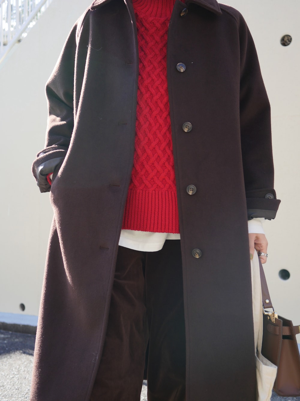 レッド系のニット/セーター、ブラウン系のショルダーバッグ、ブラウン系のステンカラーコートを着用したレディースの冬コーディネートの3枚目の写真