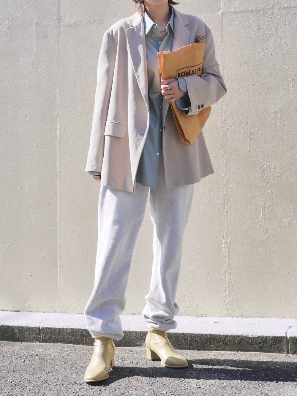 グレー系のスウェットパンツ、イエロー系のブーツ、ブラウン系のトートバッグを着用したレディースの春コーディネートの2枚目の写真