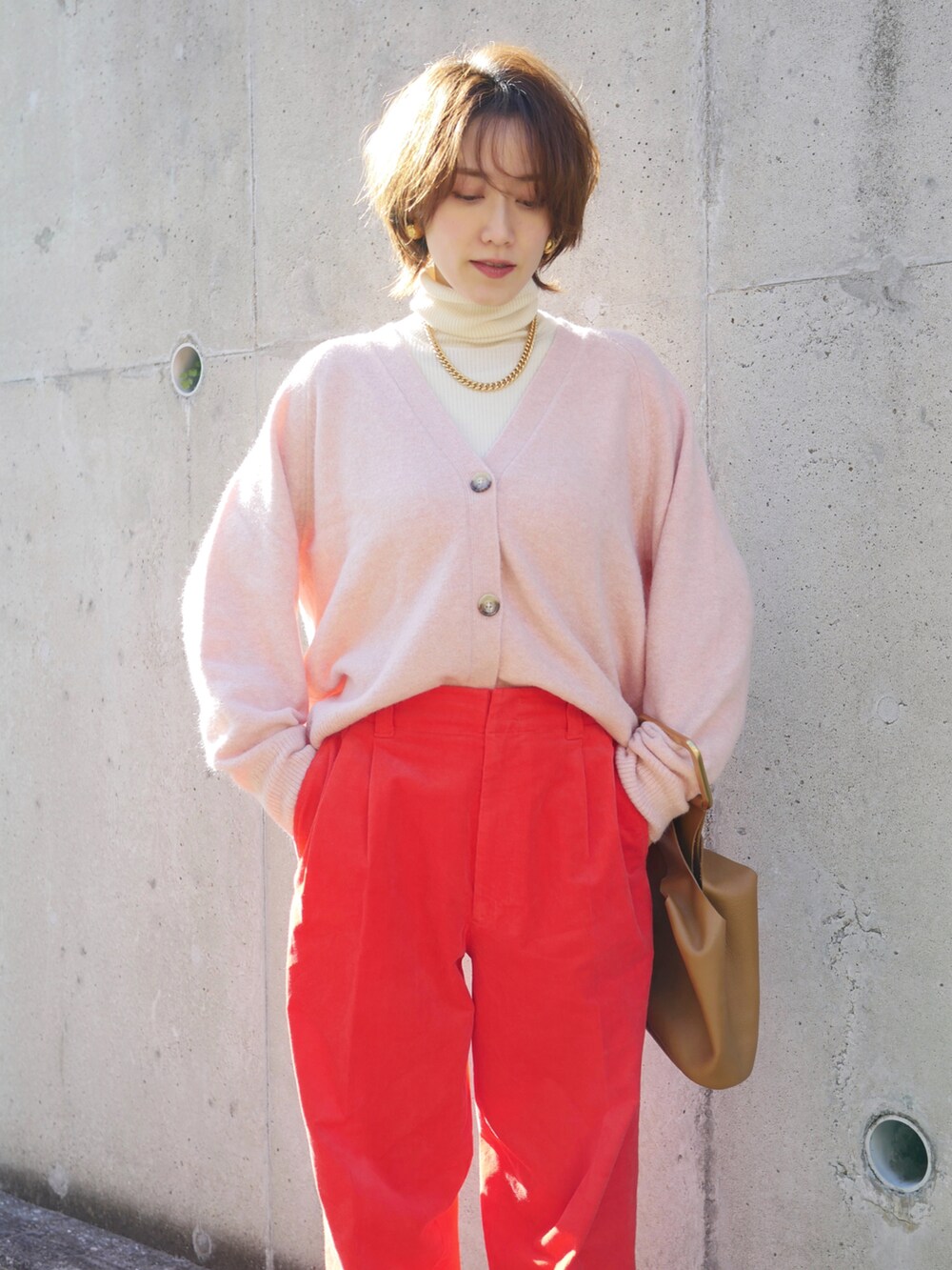 ピンク系のカーディガン/ボレロ、レッド系のパンツ、イエロー系のハンドバッグを着用したレディースの冬コーディネートの3枚目の写真