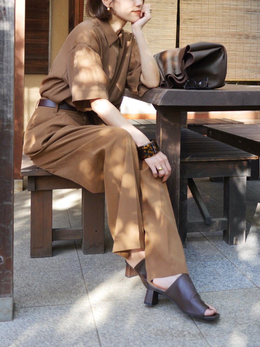 ブラウン系のシャツ/ブラウス、ブラウン系のハンドバッグ、ブラウン系のサンダルを着用したレディースの秋コーディネートの2枚目の写真
