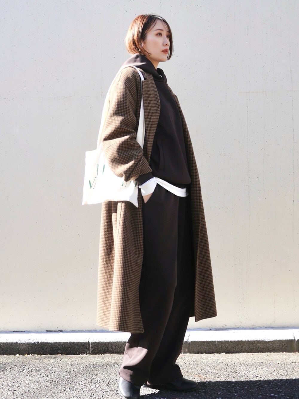 ホワイト系のトートバッグ、ホワイト系のTシャツ/カットソー、ブラウン系のチェスターコートを着用したレディースの冬コーディネートの4枚目の写真