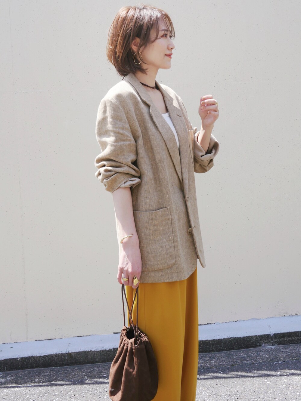 ベージュ系のテーラードジャケット、イエロー系のその他パンツ、ブラウン系のスニーカーを着用したレディースの春コーディネートの3枚目の写真