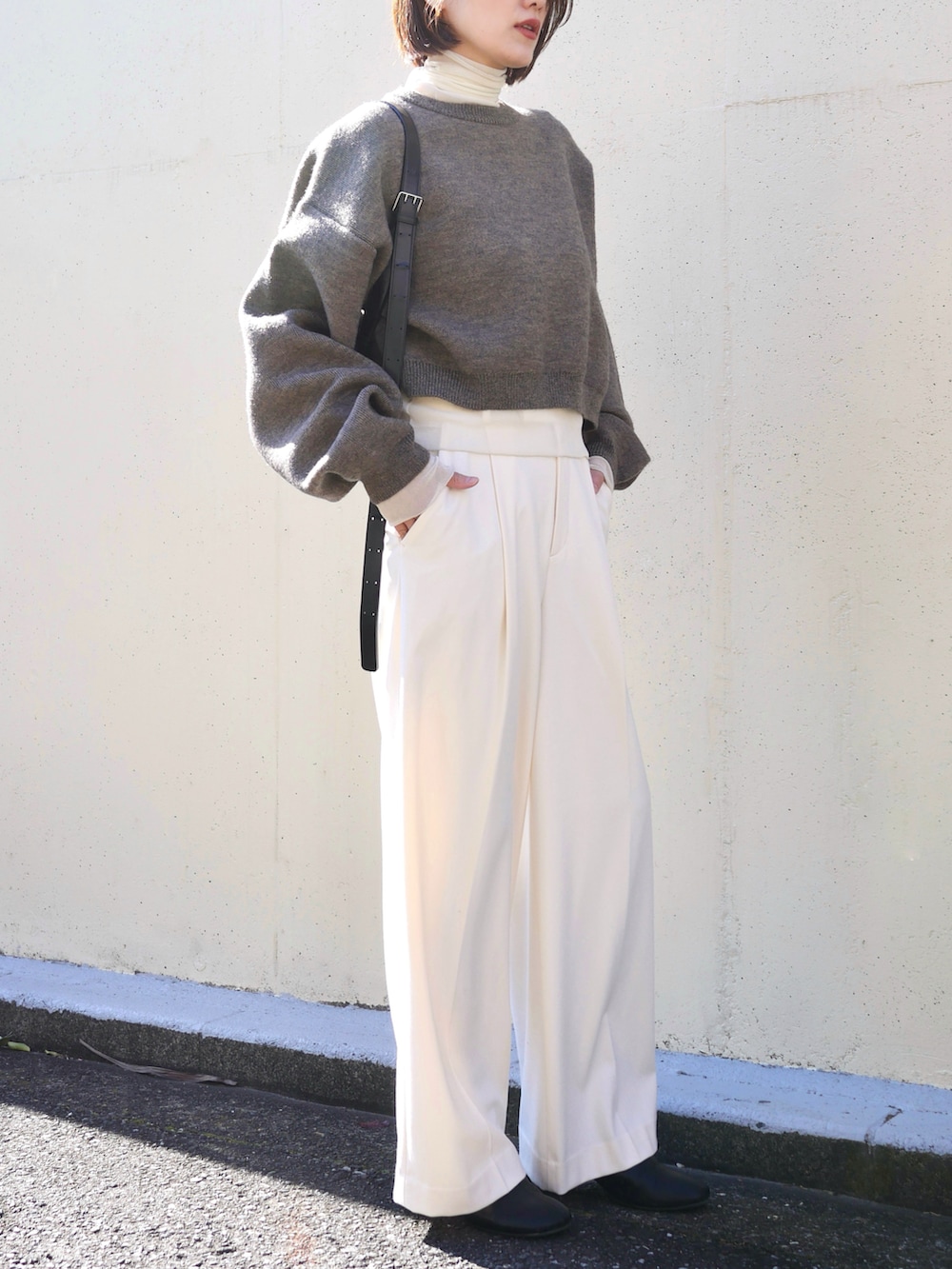 ブラウン系のニット/セーター、ブラック系のブーツ、ホワイト系のTシャツ/カットソーを着用したレディースの冬コーディネートの3枚目の写真