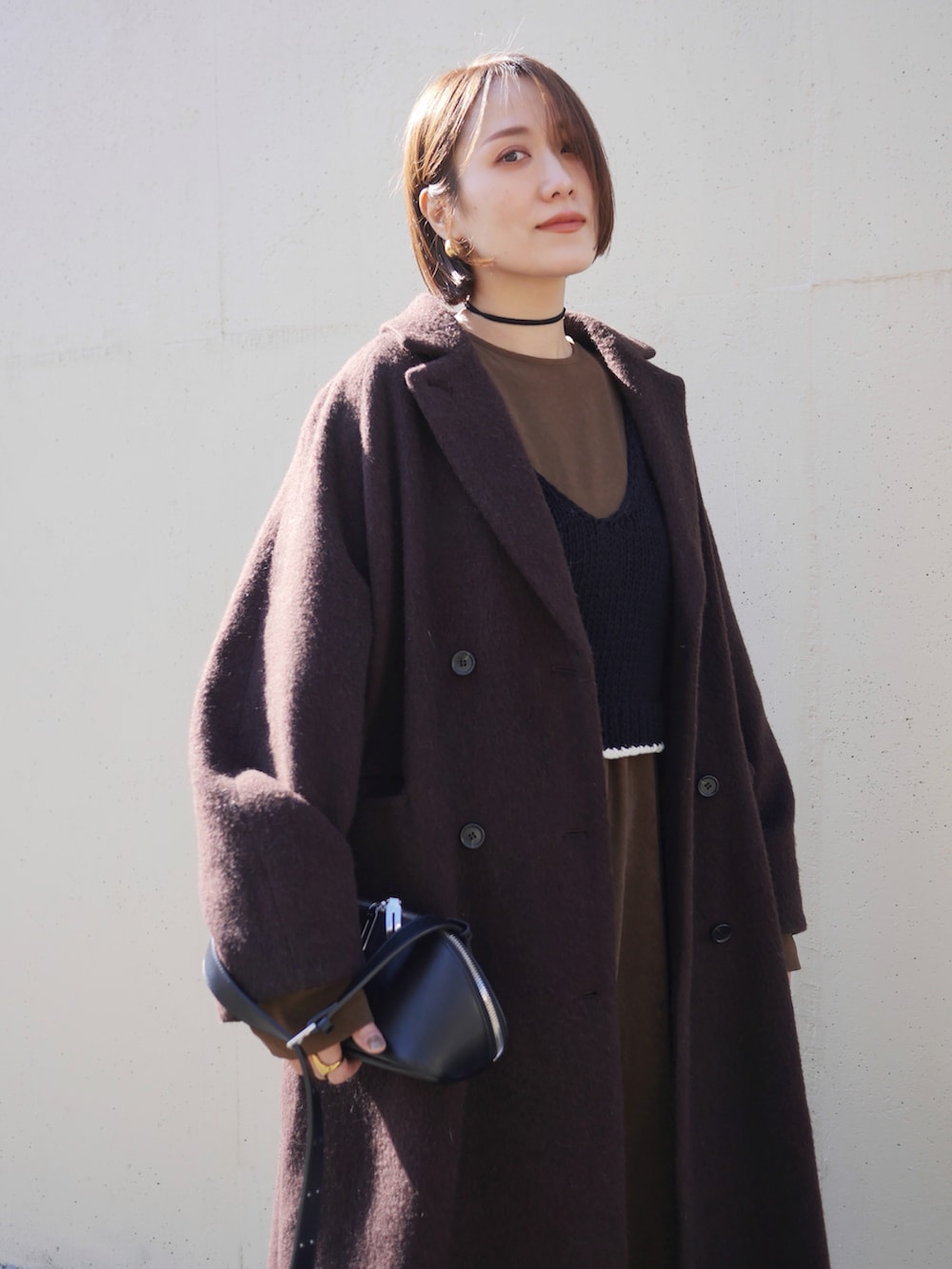 ブラウン系のワンピース、ブラウン系のその他アウター、ブラック系のニット/セーターを着用したレディースの冬コーディネートの2枚目の写真
