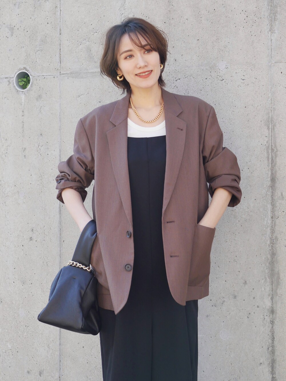 ブラウン系のテーラードジャケット、ブラック系のサロペット/オーバーオール、ブラック系のハンドバッグを着用したレディースの秋コーディネートの3枚目の写真