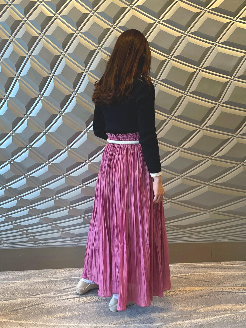 ピンク系のスカート、ブラック系のニット/セーター、ホワイト系のシューズを着用したレディースの春コーディネートの2枚目の写真