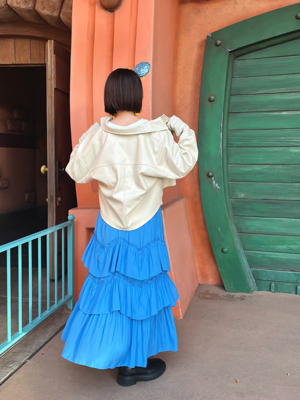 イエロー系のベスト、ホワイト系のTシャツ/カットソー、ブラック系のブーツを着用したレディースの春コーディネートの2枚目の写真