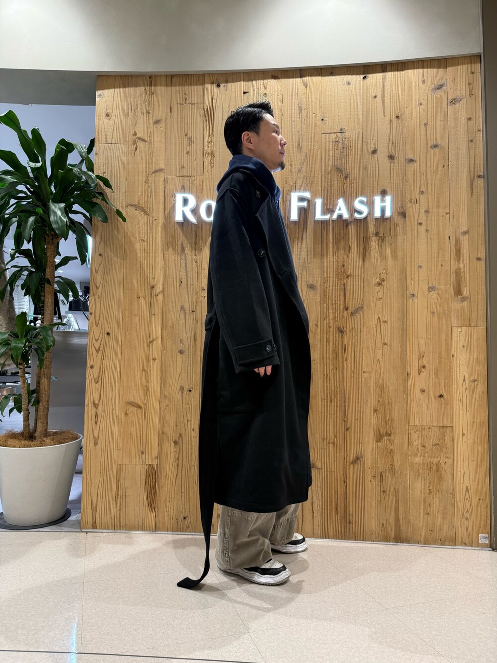 ブラック系のトレンチコートを着用したメンズの秋コーディネートの4枚目の写真