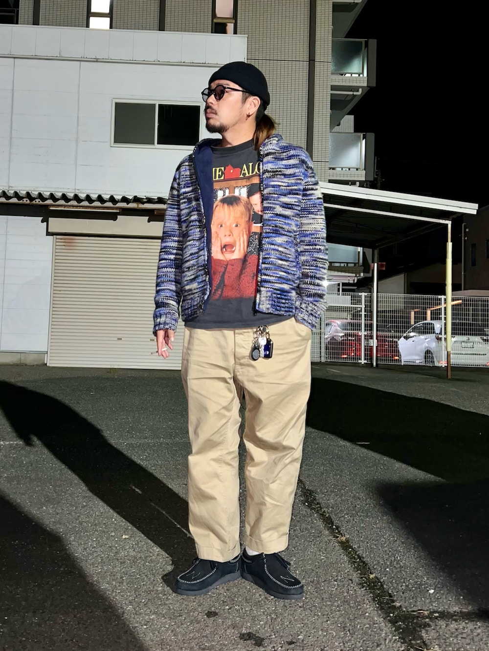 ブルー系のニット/セーター、ブラック系のTシャツ/カットソー、ベージュ系のチノパンツを着用したメンズの秋コーディネートの4枚目の写真