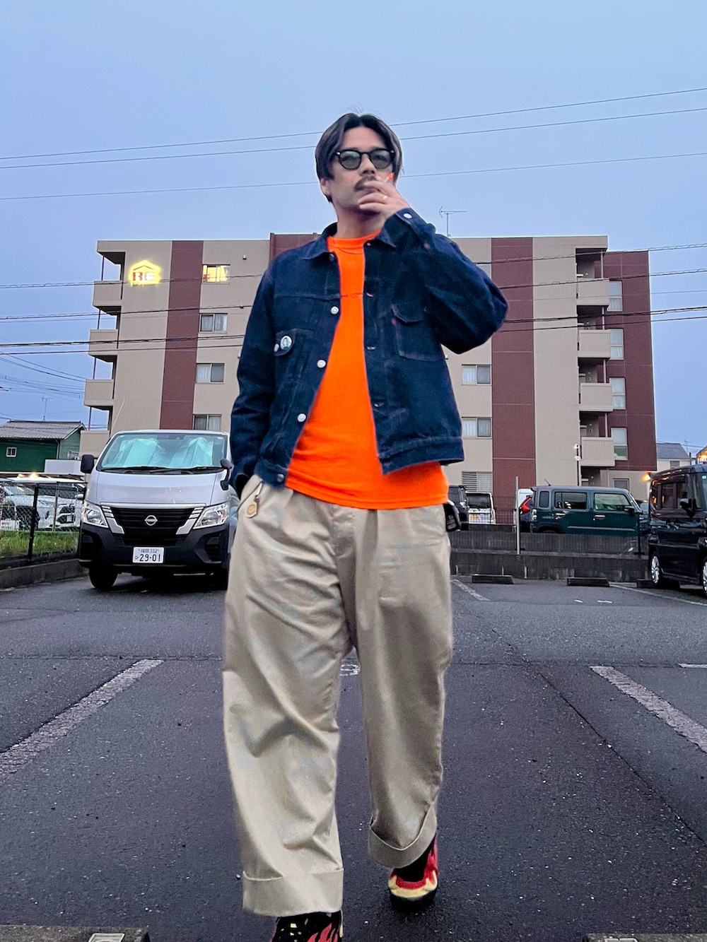 ベージュ系のチノパンツ、ブルー系のデニムジャケット、オレンジ系のTシャツ/カットソーを着用したメンズの春コーディネートの3枚目の写真